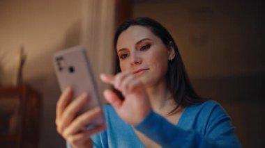Esmer kadın, internet üzerinden akıllı telefondan karanlık daireye yakın çekim yapıyor. Gülümseyen kadın gece evde cep telefonu uygulaması kullanarak internet alımlarını tatmin ediyor. Oturma odasında cep telefonu mesajı okuyan mutlu bayan..