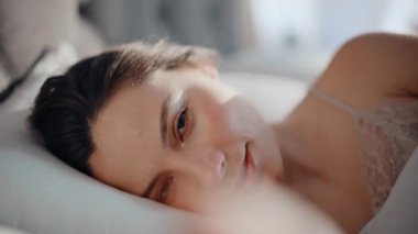 Nazik bir kadın, sabah erken kalktığında yastıkta yatıyor. Evde uyandıktan sonra gülümseyen esmer, güzel bir kamera portresi. Neşeli bayan rahat bir dairede dinleniyor Tembel hafta sonunun tadını çıkarıyor.