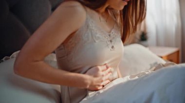 Rahat bir yatak odasında karnını tutan sıkıntılı bir kadın kendini kötü hissediyor. Karın ağrısından muzdarip yatağında yatan endişeli bir kadın. Esmer kadın sabahtan beri acı çekiyor. Yatakta uyanıyor..