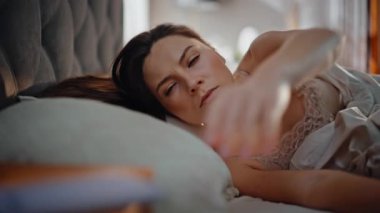 Akıllı telefon mesajı alan uyuyan kız rahat bir yatak odasında yatıyor. Güzel bir kadın sabah erkenden yatak odasında akıllı telefon okurken gülümsüyor. Mutlu bayan evde internet iletişiminin keyfini çıkarın..