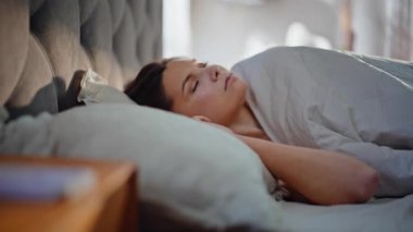 Uykulu bayan, güneşli bir otel odasında uyanıyor. Yumuşak yastıklarda oturan çekici esmer sabah tazeliğinin tadını çıkarıyor. Sakin, uykulu kadın hafta sonu evde rahat yataklarda dinleniyor..