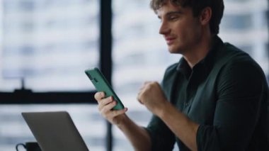 Laptop 'taki iş yerinde çalışan bir işçi cep telefonu maaş bildirimi alıyor. Gülümseyen yönetici modern ofiste akıllı telefon mesajı okuyor. Çalışma ortamında cep telefonu uygulamasını gezerken mutlu serbest çalışanlar