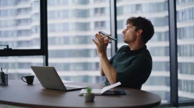 Yönetici ofisteki hoparlörde konuşan sanal ses tanıma asistanı kullanıyor. Kendine güvenen iş adamı cep telefonuyla sesli mesaj kaydediyor. Başkan hoparlörden konuşuyor.