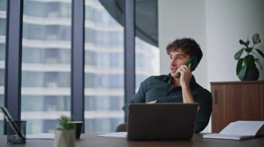 Happy direktör cep telefonunu arıyor modern ofis masasını kapatıyor. Profesyonel yönetici şirket işyerinde cep telefonuyla danışmanlık yapıyor. Şık iş adamı akıllı telefon konuşmalarıyla projeyi tartışıyor.