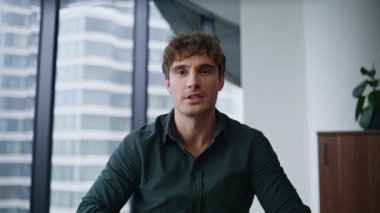 Modern ofis pov 'daki video toplantısında yönetici selamı. Yakın çekim. Gülümseyen iş adamı online konferansta iş planını tartışıyor. İş yerindeki sanal çağrıda konuşan akıllı girişimci..