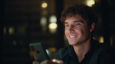 Geceleri cep telefonuna mesaj atan gülümseyen bir adam. Mutlu erkek serbest çalışan akıllı telefonlu mesaj gecenin geç saatlerinde internet iletişiminin keyfini çıkar. Ofiste cep telefonu ekranını dinleyen işadamı elleri