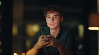 Gece müdürü karanlık şirket işyerinde SMS okuyor. Gülümseyen yönetici, akşam ofisindeki akıllı telefonu kullanarak online iletişimden zevk alır. Neşeli iş adamı telefonda online içeriği izliyor.