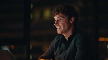 Profesyonel başlangıç videosu, gece ofisinde yakın planda. Gülümseyen iş adamı, bilgisayardaki webcam 'i selamlıyor. İnternetteki konferansı yönetiyor. Evde yapılan sanal toplantıda konuşan pozitif serbest yazar..