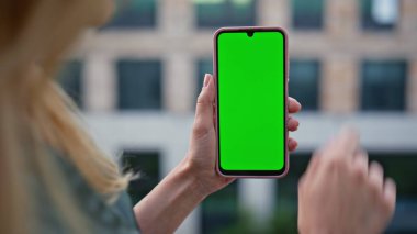 Girişimci modern mimari arka planda yeşil ekran cep telefonu uygulamasını çalıştırıyor. Bilinmeyen bayan serbest yazar yeşil ekran akıllı telefonu izliyor. İş kadını iş için cep telefonu kullanıyor