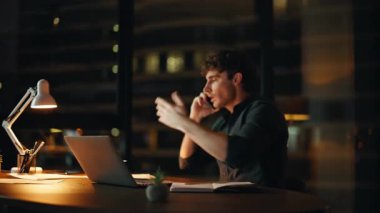 Sinirli iş adamı gece ofisinde akıllı telefonu tartışıyor. Stresli yöneticinin cep telefonu konuşması gergin bir şekilde kapanıyor. Öfkeli yönetici elinde kağıtlarla konuşmaktan bıktı.