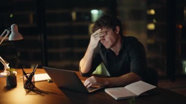 Çok çalışan yönetici, gece iş yerinde dizüstü bilgisayara bakarak bütçe planlaması yapıyor. Karanlık Ofis 'te fazla mesai yapıp defter okuyan yorgun girişimci. Yorgun iş adamı araştırma yapıyor..