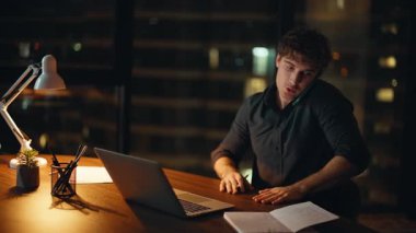 İşletme müdürü cep telefonuyla danışmanlık yapıyor. Lamba ışığı altında karanlık işyerinde oturuyor. Profesyonel danışman iş bilgisayarını arayarak sipariş veriyor. Gülümseyen işadamı işi cep telefonuyla tartışıyor.