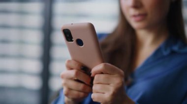 İş kadını, ofis molalarında cep telefonuna mesaj atarken elini uzatıyor. Gülümseyen iş kadını akıllı telefondan mesaj atıyor modern iş yerinde tek başına oturuyor. Şık esmer kadın cep telefonundan maaş bildirimi alıyor