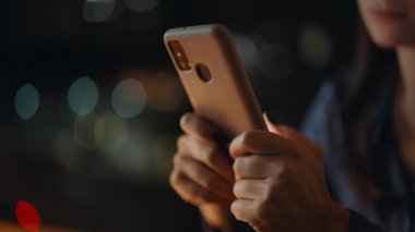 Karanlık ev kapanışında kadın elleri cep telefonuna mesaj atıyor. Gece işyerinde cep telefonundan mesaj yazan serbest çalışan bir kadın. Genç iş kadını, gece geç saatlerde akıllı telefondan bildiri yazıyor..