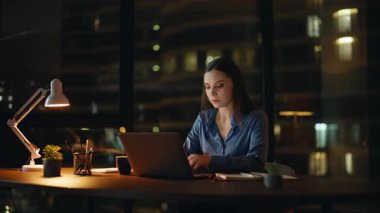 Kadın yönetici gece geç saatlere kadar çalışıyor. Ciddi bir iş kadını karanlık bir iş yerinde lamba ışığında dizüstü bilgisayar yazıyor. Fazla mesai yapan bayan çalışanlar fazla mesai yapmayı düşünüyor. İşçi aşırı yüklenmesi.