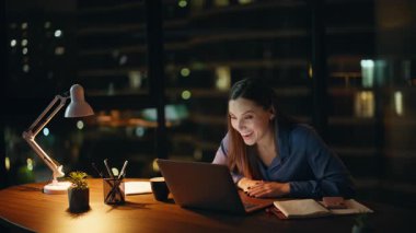 Mutlu Bağımsız Karanlık Ev İş Yeri 'nde video görüşmesinin tadını çıkarın. Gülümseyen iş kadını internet görüşmesini bitirdi ve laptop web kamerasına veda etti. Neşeli kadın çalışanın gülen videosu gece ofisinden arıyor.