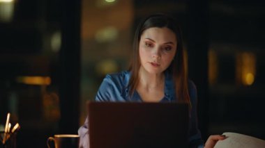 Akşam işyerinde internetten ders çalışan genç bir kadın. Akıllı yönetici dizüstü bilgisayarda eğitici web sitelerini izliyor. Not defterine notlar yazıyor. Fazla mesai yapan bilgisayardan gelen zarif esmer not verileri.