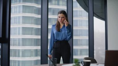 Şirket çalışanı cep telefonuyla konuşan çağdaş ofis alanı. Başarılı bir iş kadını cep telefonunu arıyor ve laptoptaki verileri kontrol ediyor. Gülümseyen kadın yönetici akıllı telefonla müşteriye danışıyor.