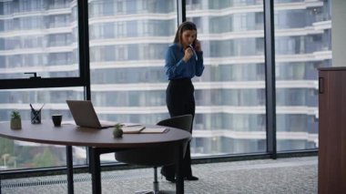 Çağdaş ofiste akıllı telefondan konuşan kadın uzman. Kendine güvenen iş kadını laptopta telefonla bilgi arayarak işi tartışıyor. İş yerinde konuşan zarif esmer müdür..