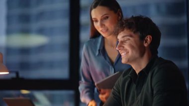 İş arkadaşları video konferansında karanlık çalışma alanına yakın oturuyorlar. Gülümseyen iş kadını işadamı çevrimiçi toplantıda proje sunuyor. Arkadaş canlısı iş arkadaşları sanal çağrı yoluyla yaratıcı fikirleri paylaşıyorlar