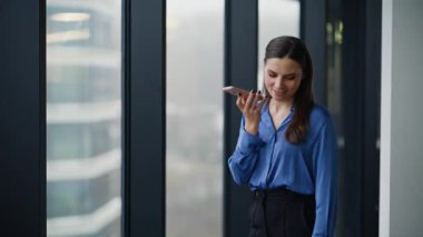 İş kadını, iş merkezinin penceresinde duran ses kaydını kaydediyor. Gülümseyen kadın cep telefonuyla sesli mesaj yolluyor. Akıllı telefon hoparlörüyle konuşan zarif bayan patron..