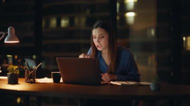 Kadın patron sanal konferansta tartışıyor. Gece ofisindeki bilgisayar kamerasına evrakları gösteriyor. Sinirli bir iş kadını video araması yüzünden tartışıyor. Gergin esmer iş sorunları hakkında konuşuyor..