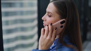 Yakın çekim yöneticisi akıllı telefon görünümlü ofis panoramik penceresinden bahsediyor. Gülümseyen iş kadını cep telefonunu arıyor ve çalışma alanındaki projeyi tartışıyor. Seçkin yönetici hanım cep telefonu iletişiminin keyfini çıkarın..