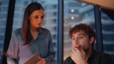 İşletme hocası, akşam ofiste bilgisayarla çalışan bir stajyerle konuşuyor. Kadın patron, erkek yönetici projesini inceliyor. Tabletteki verileri açıklıyor. İş kadını, genç çalışana danışarak işi tartışıyor.