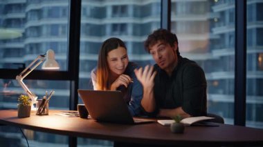 Meslektaşlar karanlık iş yerinde sanal konferansı bitirirler. Uzaktan kumandalı iş görüşmelerinde iki iş arkadaşı ofiste dizüstü bilgisayar görüntülü web kamerası görüntüsü veriyor. İnternetteki toplantıda gülen ortaklar akşam geç saatlerde konuşuyor..