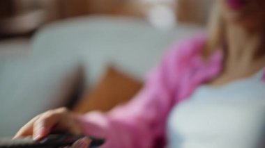 Kapalı el değiştirme kanalı. Haftasonu evde uzaktan kumanda var. Şaşırmış mutlu kızın portresi kanepede televizyon filmini seçiyor. Neşeli sarışın kadın evde televizyon seyrediyor. 