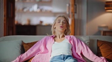 Yorgun sarışın koç kendini çok yakın hissediyor. Uykucu serbest çalışan kadın, oturma odasında migreni tutuyor. Yorgun kız yumuşak koltukta oturuyor. Rahat bir evde tek başına dinlenmeye çalışıyor. 