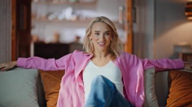 Kaygısız bir kadın evde kanepeye oturuyor. Neşeli sarışın kız, oturma odasında dinlenme koltuğunda dinleniyor. Tatmin olmuş bir bayan mutlu görünüyor. Kameralar rahat bir dairede dinleniyor.