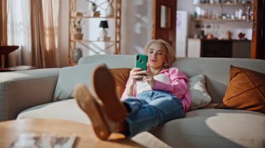 Rahat koltukta dinlenen akıllı telefon görünümlü yalancı kız. Huzurlu tatilde cep telefonundan mesaj okuyan hayalperest romantik bayan. Alıştırma uygulamasında sanal alışverişe karar veren çekici bir kadın.