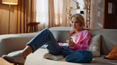 Bilgisayar okuyan kız öğrenci oturma odasındaki koltukta oturuyor. Tablet evde sosyal medyada komik videolar izleyen gülen bir kadın. Rahat serbest çalışan, ara verme sekme aygıtı kullanıyor