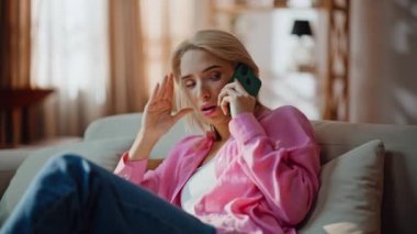 Güneşli odada cep telefonuyla konuşan üzgün bir kadın. Mutsuz, üzgün, akıllı telefon arayan, evde baş ağrısı çeken bir kız. Stresli, sinirli kadın çağrı üzerine şikayet ediyor. Depresif ruh hali duygusal çöküntü