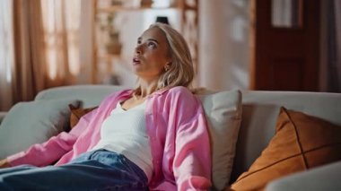 Yorgun bir kadın kanepede rahat bir şekilde oturur yorgunluk hisseder. Pembe gömlekli bitkin bir kadın rahat kanepeye sorunlarla dolup taşıyor. Stresli kız başağrısı çekiyor. 