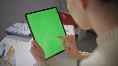 Chromakey tablet öğretmeni ev ofisinin kapanışında interneti tarıyor. Modern iş yerinde yeşil ekran ekran bilgisayarı tutan özel hocalar yalnız çalışıyor. Model aygıtı kullanan bilinmeyen kadın 
