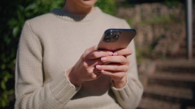 Sunny Park 'ta yürürken cep telefonuna mesaj atan bir kız. Tanımlanamayan zarif bir kadın açık havada modern akıllı telefondan ekranda yazı yazıyor. Bahçede telefon kullanan tanınmamış şık bir bayan.