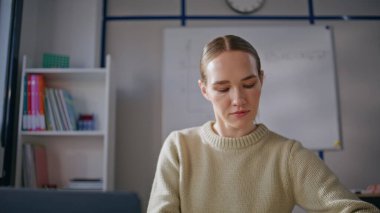 Gözlüklü bayan okulda online ders vermeye hazırlanıyor. Genç bir kadın bilgisayar ekranı oturma yeri arıyor. Zeki öğretmen sanal toplantıda öğrencileri selamlarken gülümseyerek dinliyor.
