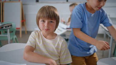 İlkokul resmine bakan sevimli çocuk kamerası. Ciddi bir çocuk mola sırasında oturma dersinde rahatlıyor. Sınıfta poz veren zeki bir öğrenci. Küçük okul çocuğu sınıfta öğretmenini dinliyor. 