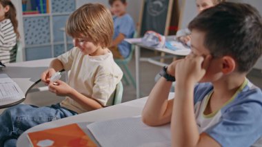 İki çocuk okulda yakın çekim dersinden bahsediyor. Sınıfta gülen sınıf arkadaşının notlarını okuyan komik çocuk. Masalarda oturan sevimli öğrenciler. Meraklı çocuklar kabinede birbirleriyle iletişim kurarken eğleniyorlar.