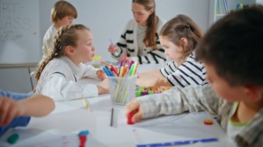 Yetenekli çocuklar stüdyoda birlikte resim yapıyorlar. Oditoryumdaki çocukla resim yapan genç öğretmen. Yaratıcı kadın ressam çocuklarla atölye çalışması yapıyor. Sınıfta aktif öğrenci çizimi