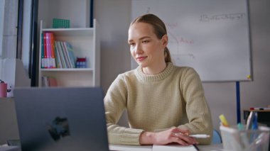 İnternetteki derste gülümseyen kadın dizüstü bilgisayarla sınıfta yakın çekim yaparak ders veriyor. Sosyal ağlarda eğitim kanalını yöneten zeki bir öğretmen. Bayan Bilgisayar Yönetme Eğitimi Kursu 