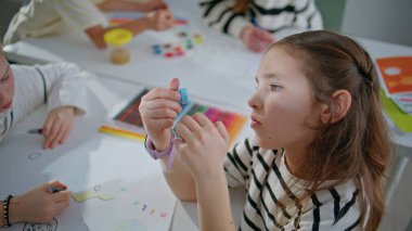 Komik kız, elinde pul tutarak okul odasında resim yaratıyor. Seminerde sınıf arkadaşlarıyla resim çizen küçük bir kız. Sınıfta resim yapmaya meraklı küçük bir çocuktan ilham aldım. Yaratıcılık kavramı 