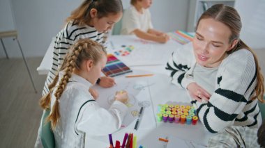 Çizim atölyesinde çocuklara resim öğreten yetenekli ressam kadın. Öğrenci öğretmeni sanat okulunda sanat eseri yapıyor. Modern stüdyoda resim yapan küçük kızlar ve kadınlar. Yaratıcılık kavramı