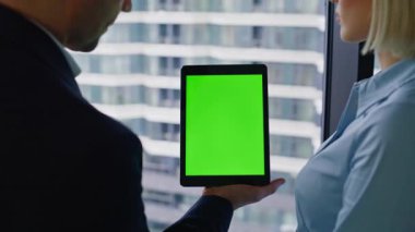 İş arkadaşı yeşil ekran tabletine tıklayarak iş kadını yakınlaştırmasını gösteriyor. İş adamı bilgisayardan meslektaşına bilgi veriyor. İş ortakları krom anahtarlı dijital aygıt arıyor