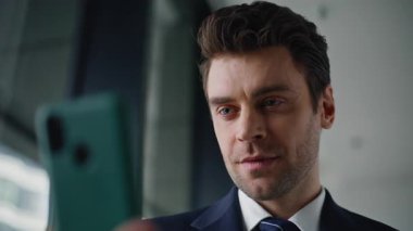 Şirket sahibi, şirket binasında cep telefonu bankacılık uygulamasına göz atıyor. Modern ofiste akıllı telefonu tutan kendine güvenen işadamı elleri. Gülümseyen adam içeride cep telefonu mesajı okuyor..