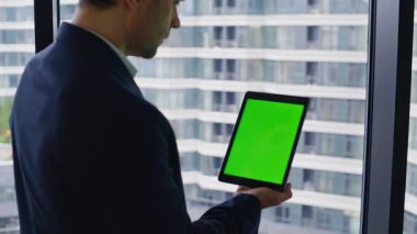 Ofis penceresinde yeşil ekran tableti tıklama çevrimiçi tarama uygulaması yakınlaştır. Zarif bir iş adamı bilgisayarına dokunuyor. Krom anahtar aygıtının finansal verilerini okuyan kendinden emin bir CEO..