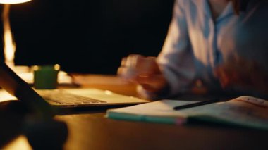 Çevrimiçi öğrenci gece ders çalışıyor. Ev masasında deftere yazı yazıyor. Yakın plan. Karanlık, ücra bir ofiste dizüstü bilgisayar yazan odaklı bir kadın. Ciddi bir iş kadını kahve içiyor ve fazla mesai yapıyor..