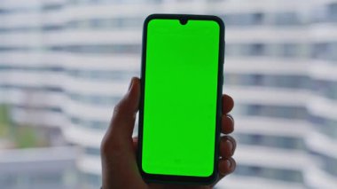 İş adamı, pencere kenarı manzarası yakınında yeşil ekran cep telefonu tutuyor. Tanımlanamayan serbest çalışan, evde krom tuşlu akıllı telefon izliyor. Adam yöneticisi model cep telefonunda bankacılık uygulamasına göz atıyor.